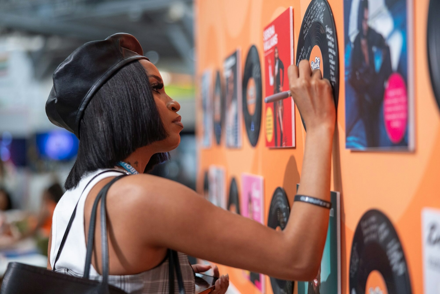 Black woman writing a message on an autographed wall