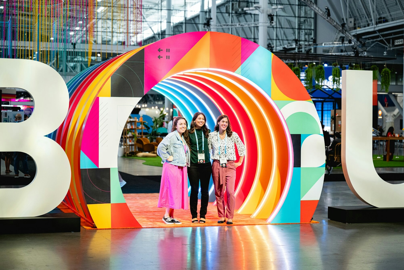 Three women pose for a picture in a colorful tunnel