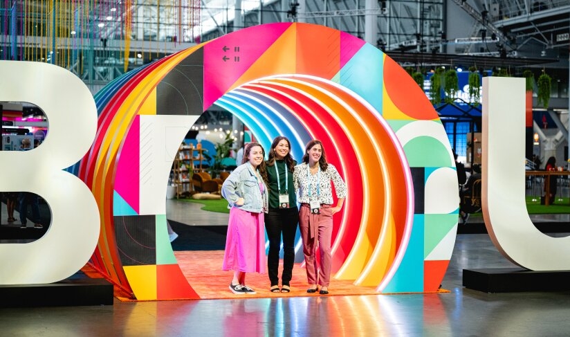 Three women standing in front of a large INBOUND logo